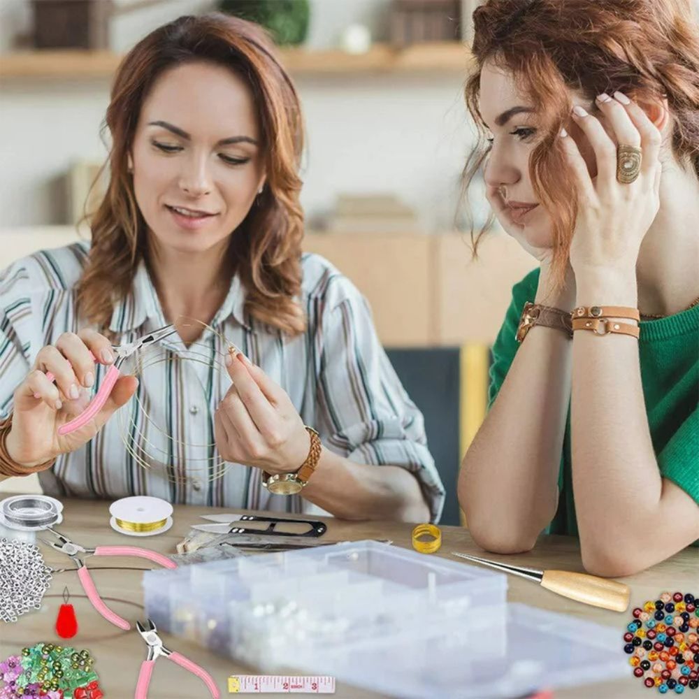 Two women engaged in jewelry-making activity at a table.